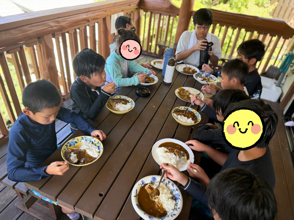 キャンプでカレーを食べる子どもたち