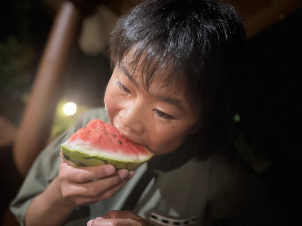キャンプでスイカを食べる子ども