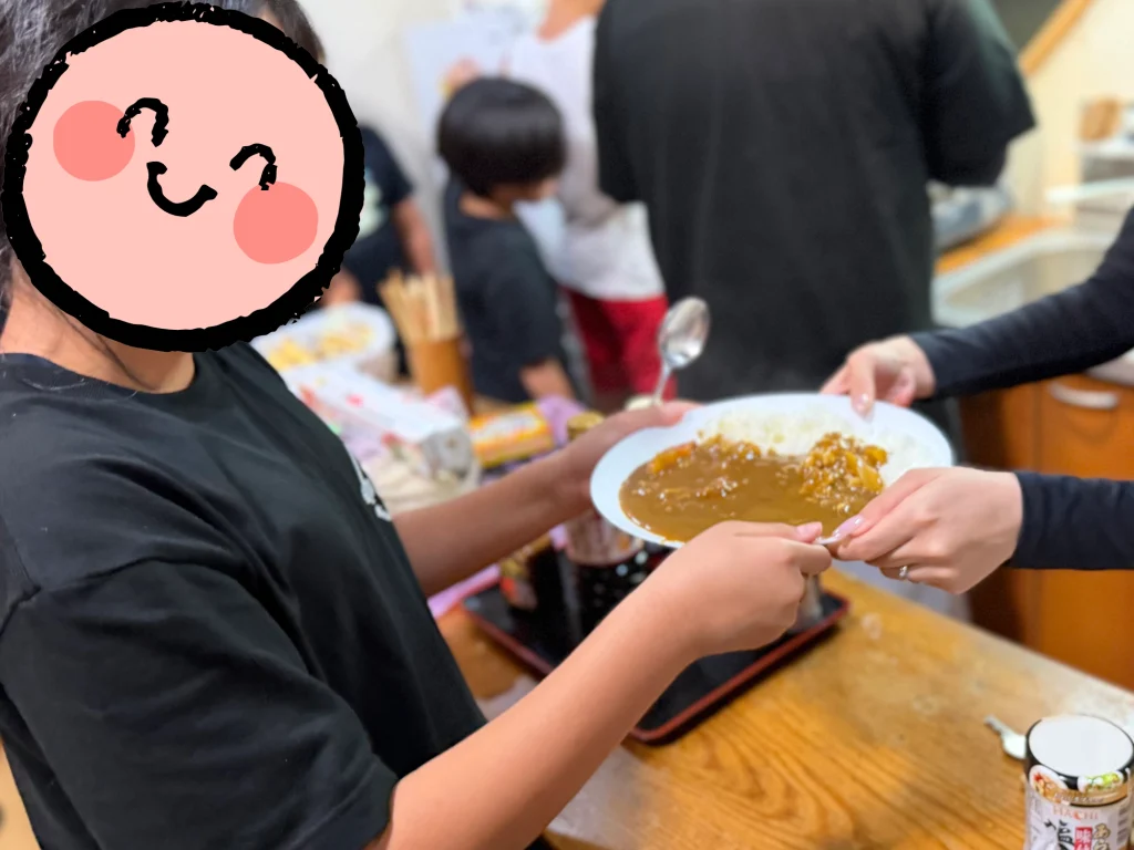 森のコテージでカレーを注いでもらう子ども