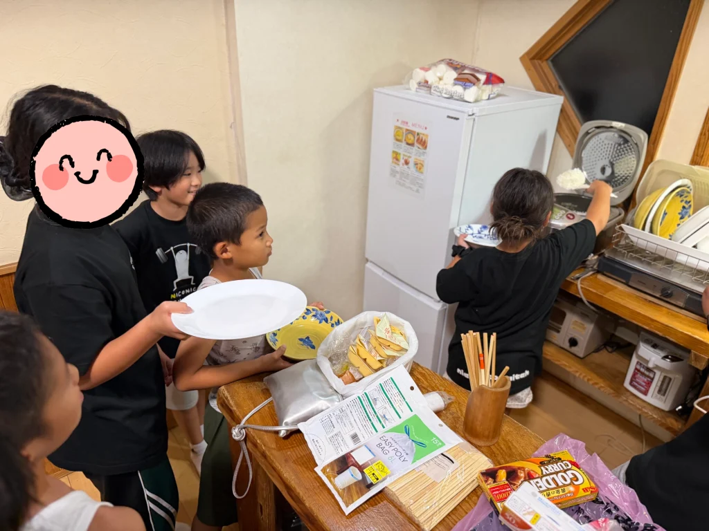 森のコテージで夕食のご飯を注ぐ子どもたち