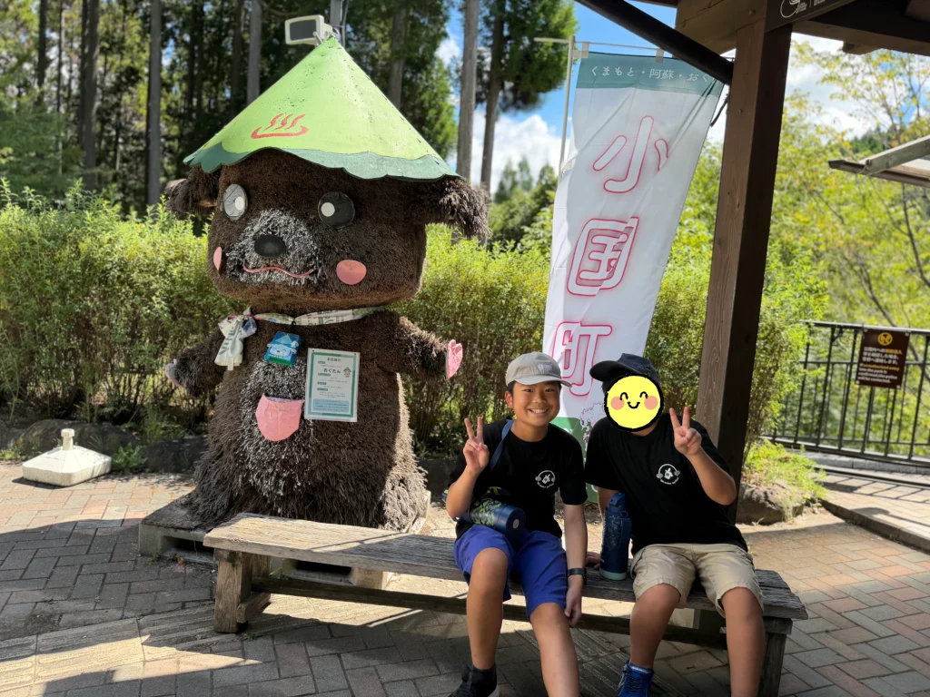 鍋ヶ滝の入り口のおぐたんの前で記念写真を撮る子どもたち