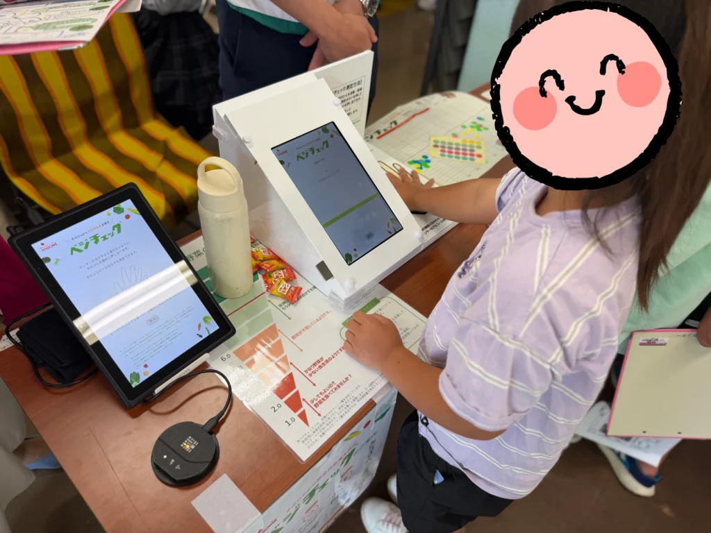 ベジチェックで野菜摂取量を測定する子ども