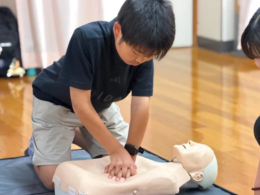 胸骨圧迫（心肺蘇生）の体験をする子ども