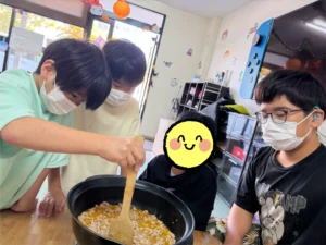 麻婆豆腐作りで木べらを使って鍋の中を混ぜる子どもたち