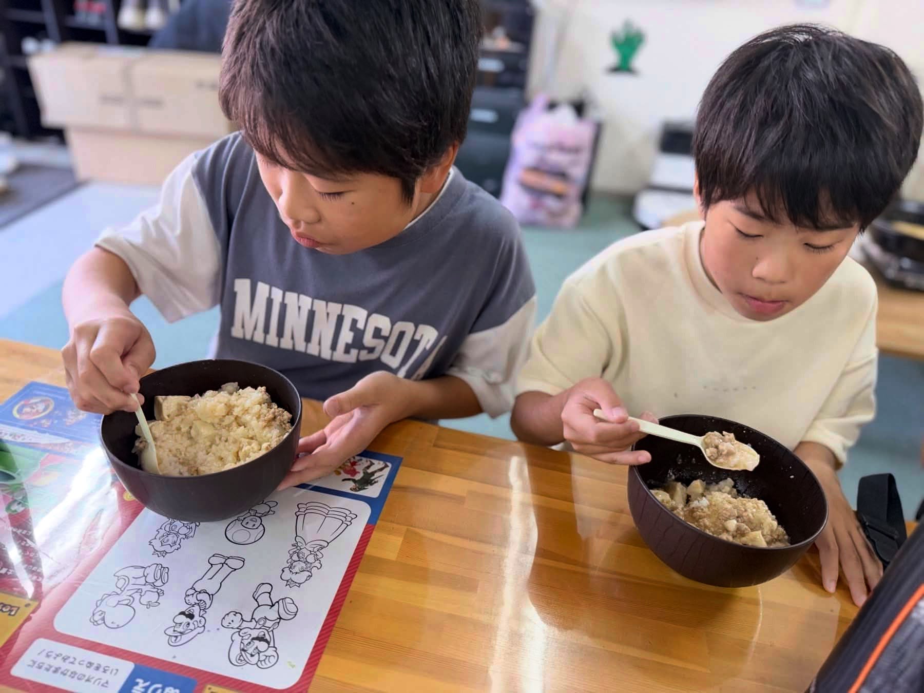 できあがった麻婆豆腐をスプーンで食べる子どもたち